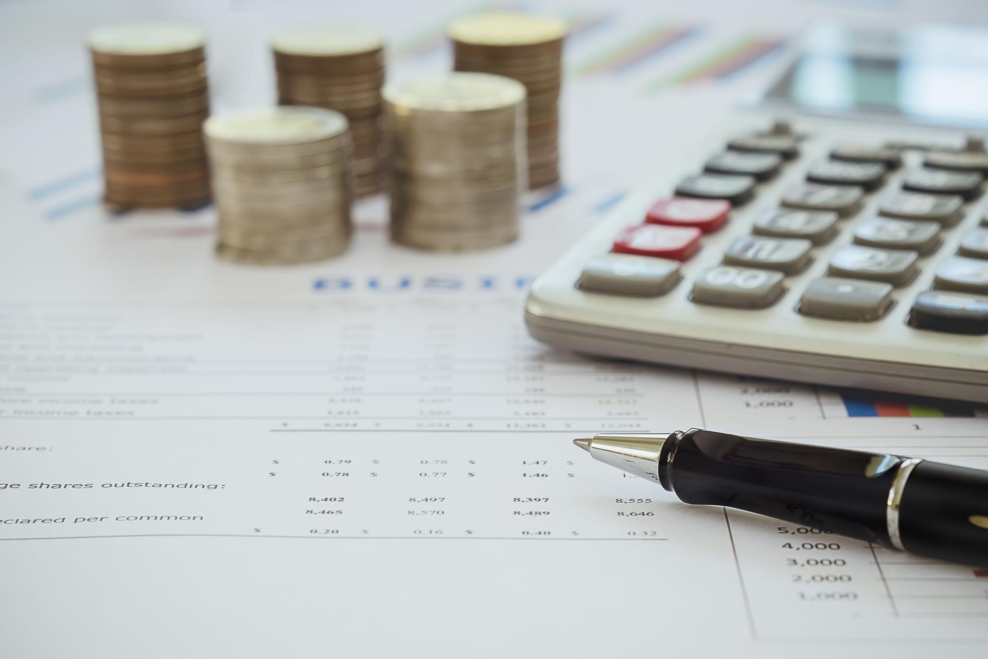 argent en pièces avec stylo et calculatrice