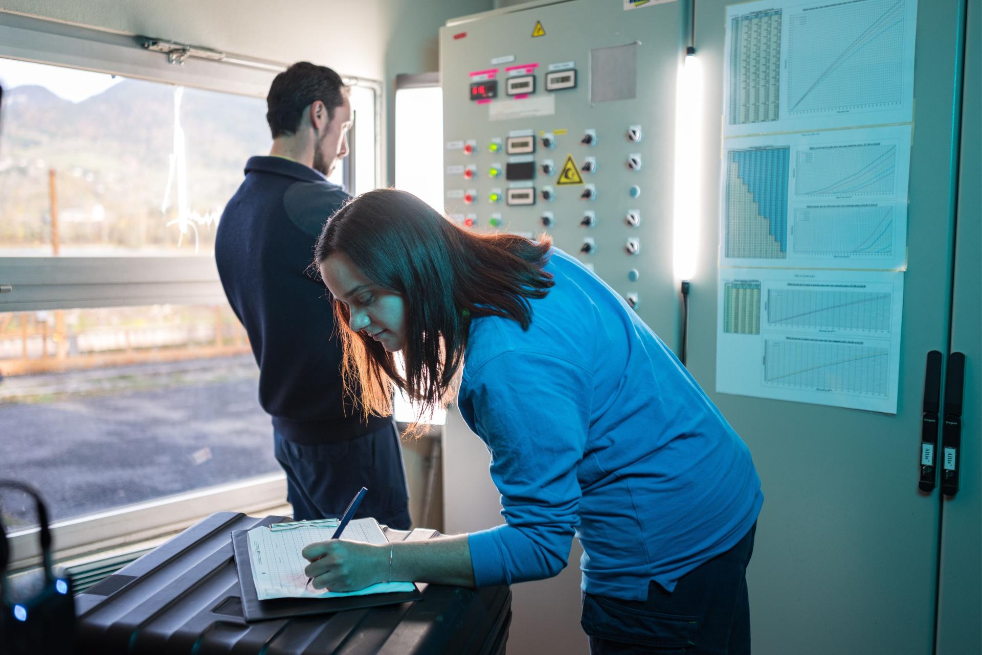 jeune femme qui écrit et 1 homme sur poste