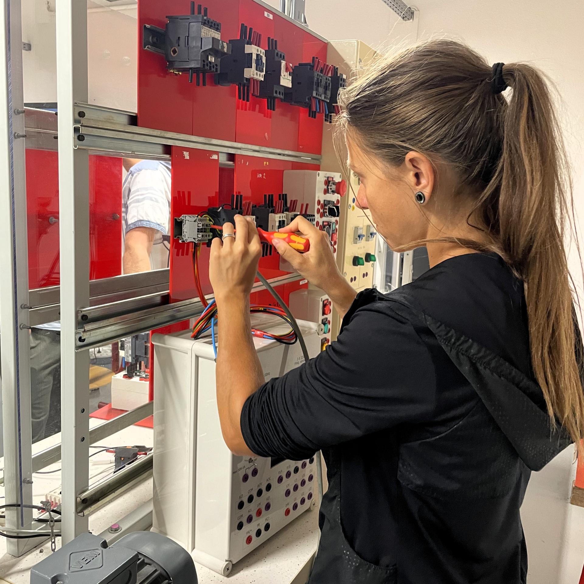 jeune femme manipule une installation électrique