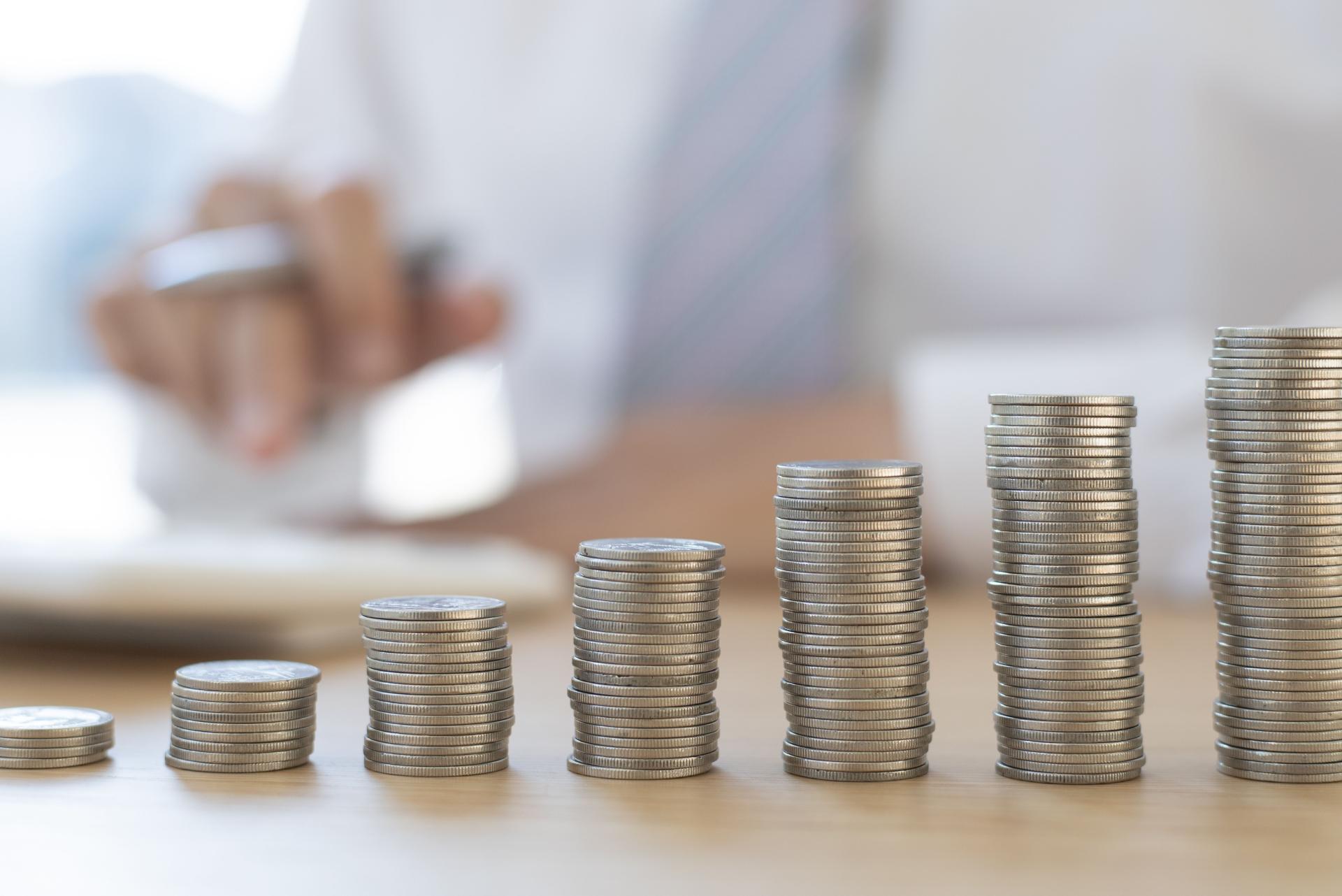 Pièces empilées et main avec calculatrice