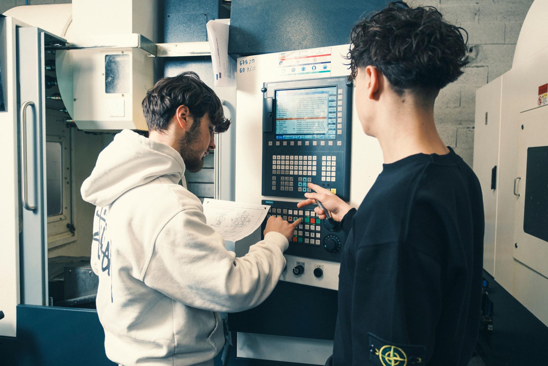 2 jeunes apprentis usineurs sur machines à commandes numériques