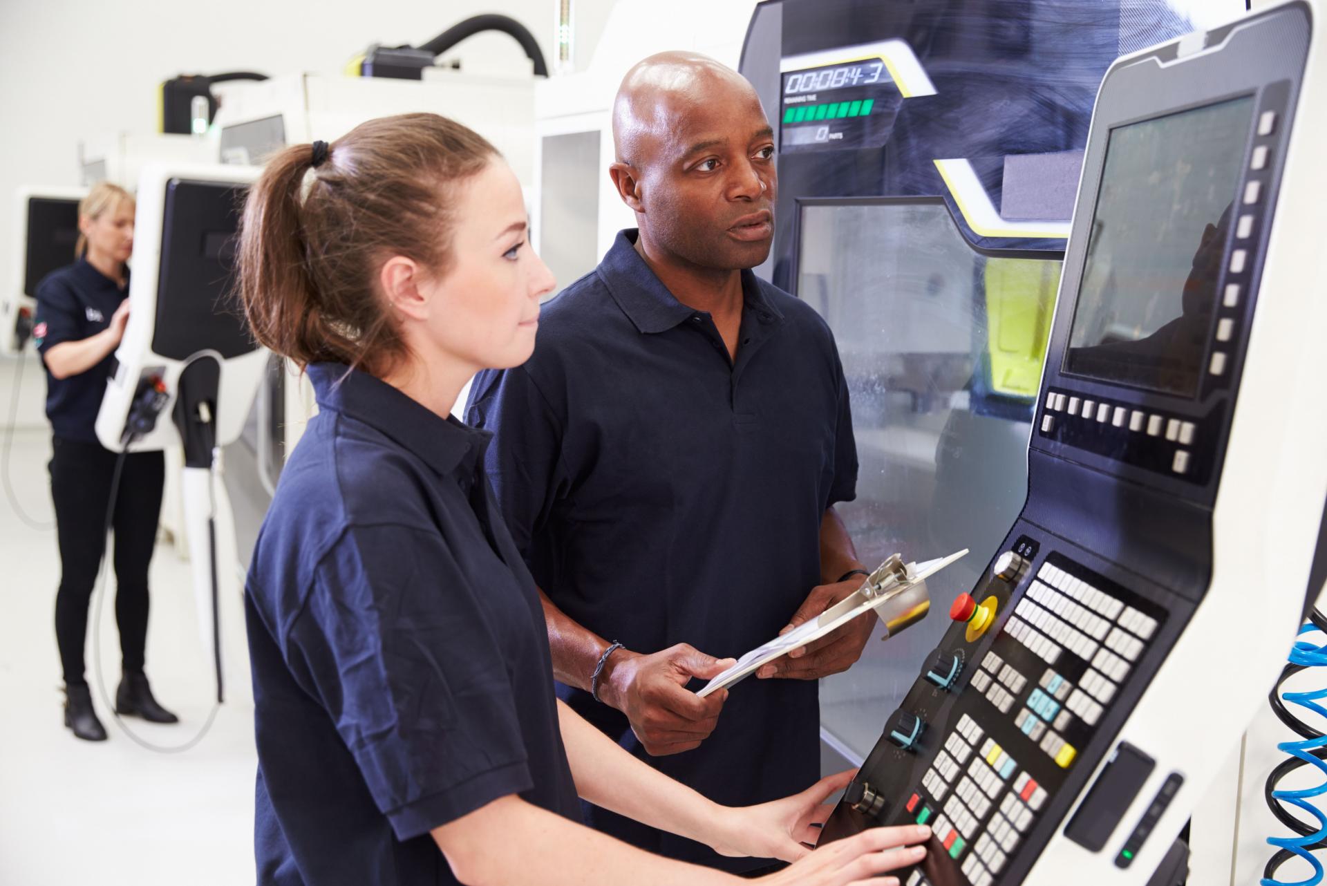 Tuteur et jeune fille en apprentissage sur machine CN usinage