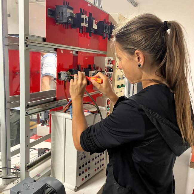 jeune femme manipule une installation électrique